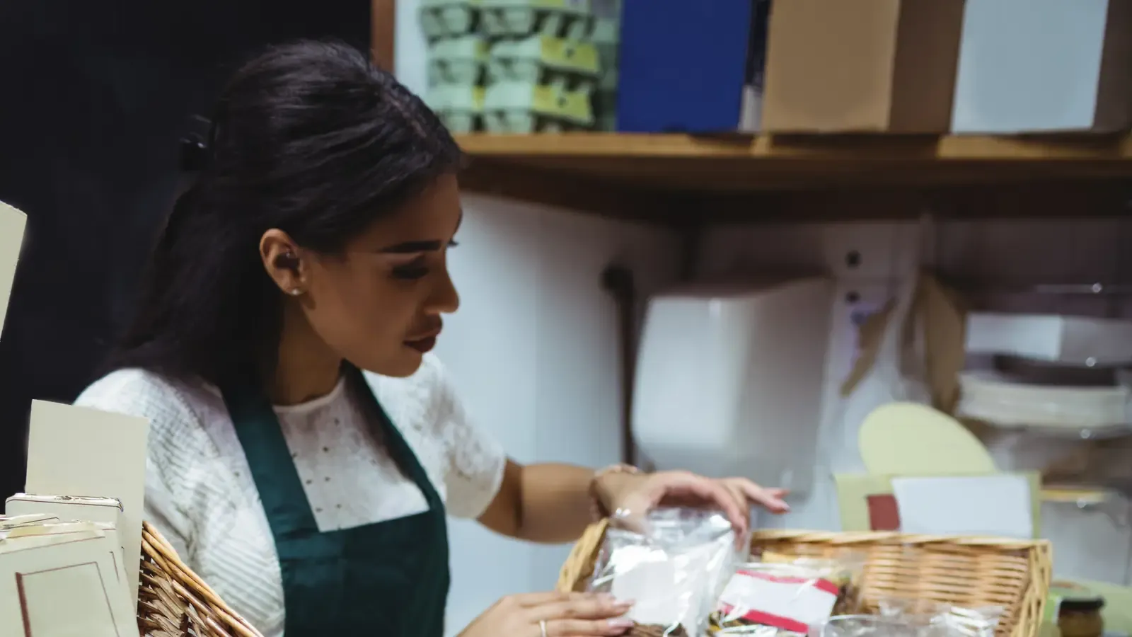 Confeiteira de avental embala um produto no balcão da loja